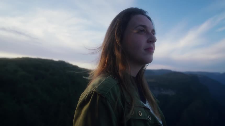 A woman stands looking out at the mountain ridge and valley with a look of wonder on her face