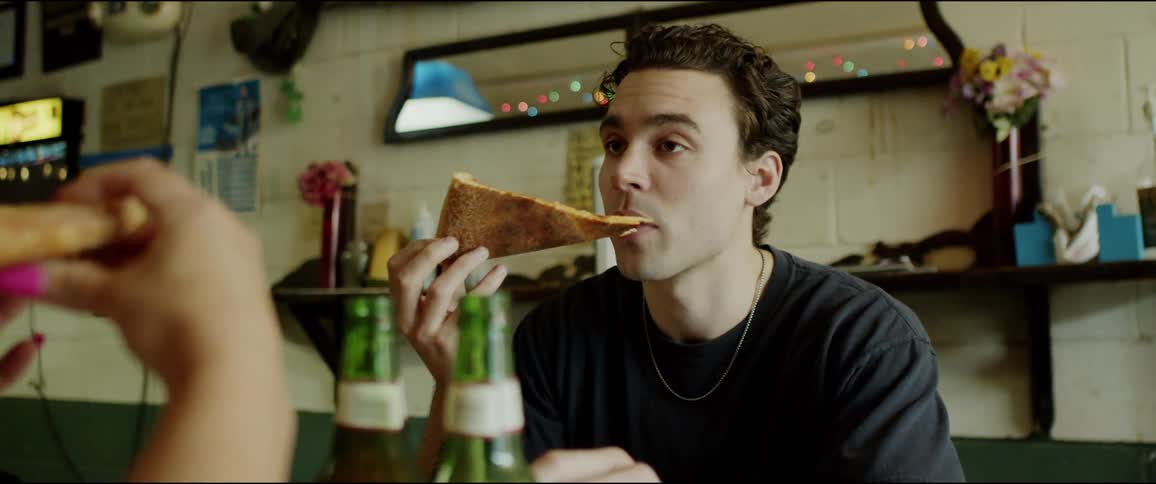 A man chats with a woman as they eat pizza together in a restaurant during the day