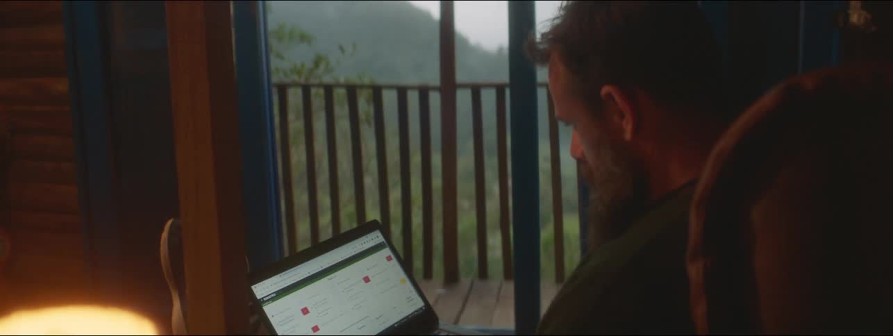A man sits in his home and types on a laptop