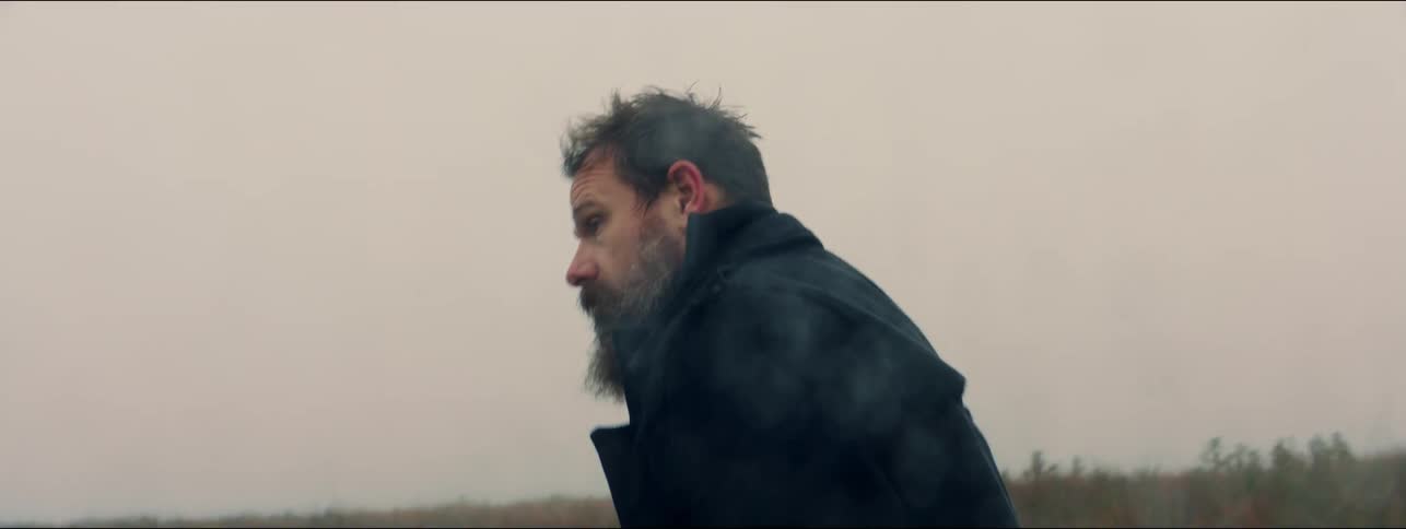 A man walking around outdoors in a jacket in a rainy day