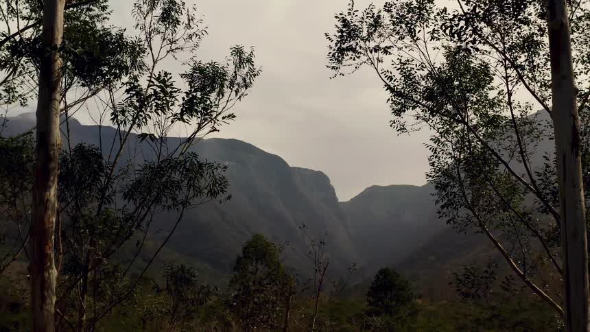 Aerial view of distant high mountains and valley seen from forest