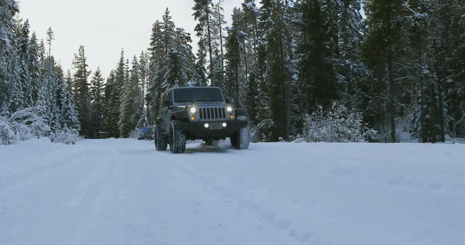 A jeep travels along a snow covered road