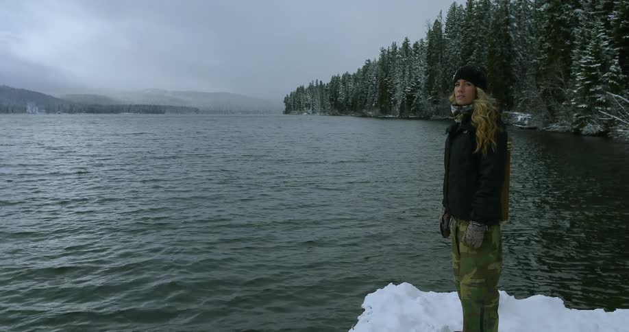 A woman stands near the water looking around