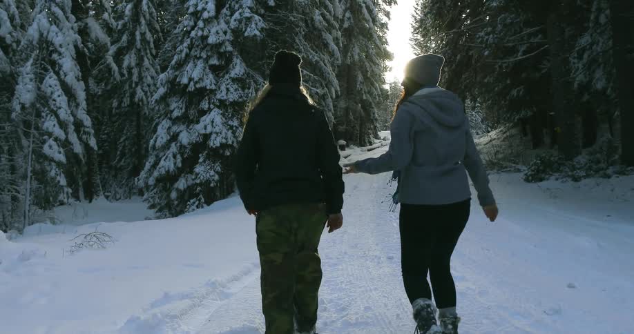 Two women get out of a jeep and walk up a snow covered road