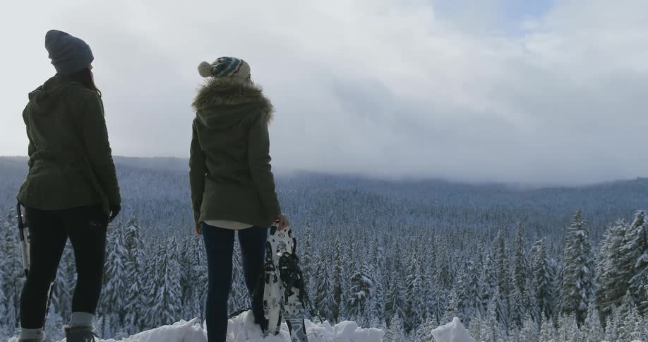 Two women stand on the edge of a cliff looking over