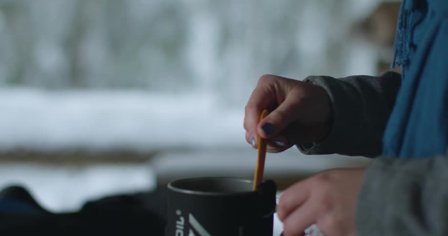 A person stirs a cup with a wooden spoon