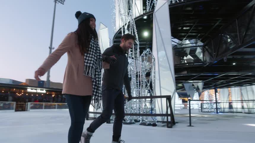 Couple play ice skating at the evening