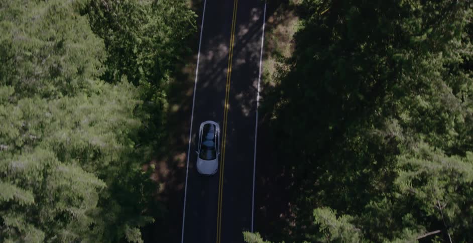 A white car travels down a road on a sunny day