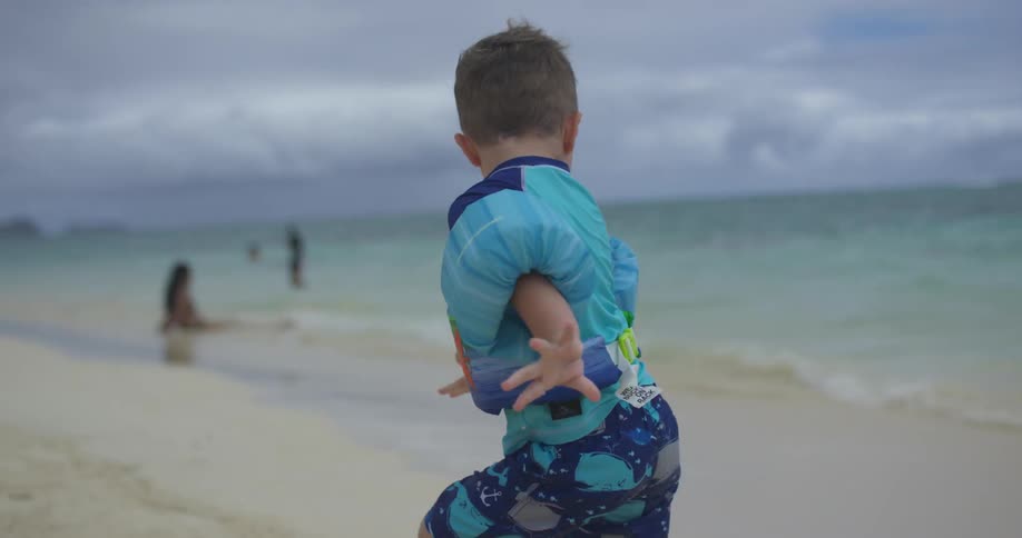 A boy runs from some waves on a beach