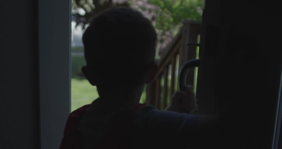 A boy opens a door to to the sunny outside