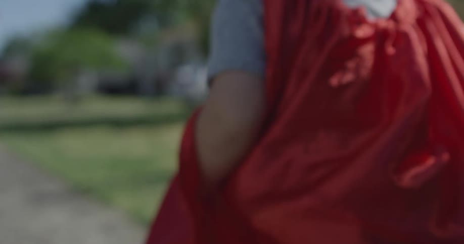 A boy wearing a cape and mask is running