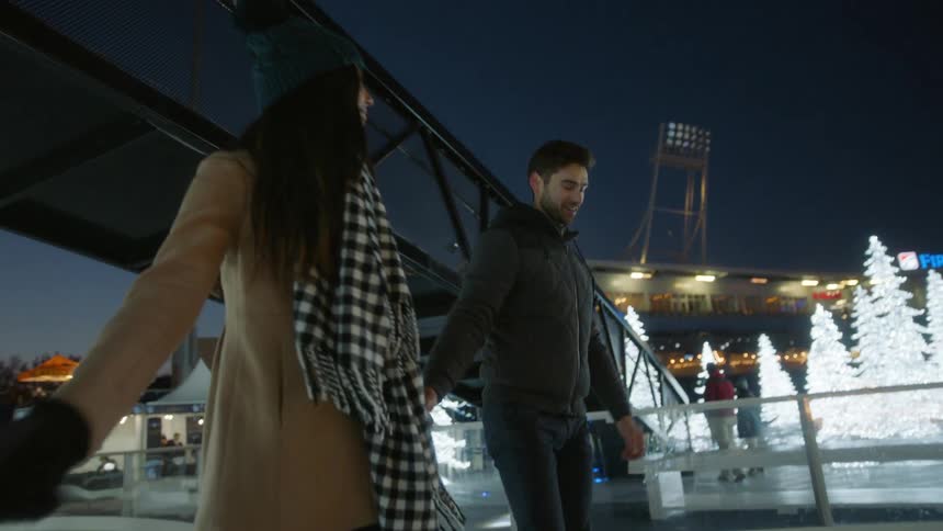 A man and woman skate while holding hands