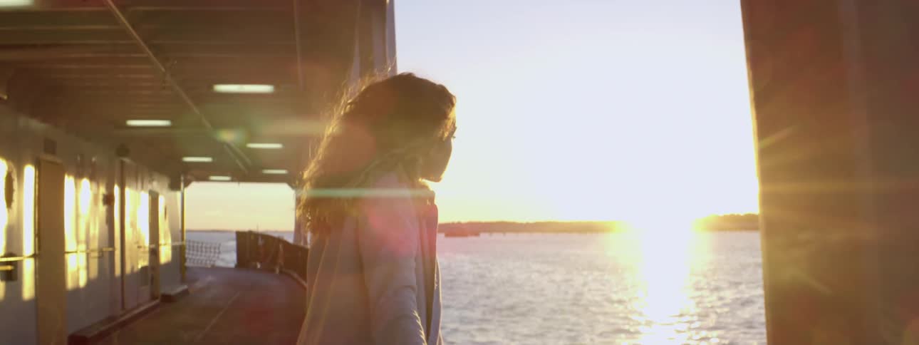 A woman leans on the railing of a boat looking over
