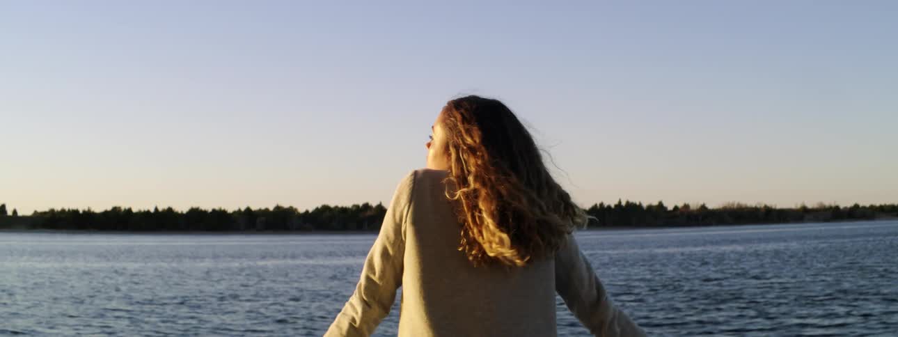 Woman standing at the railing's edge watching the water pass by