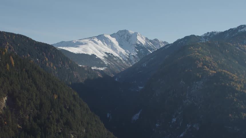 Mist covers forested mountains backed by mountain with a snow capped summit