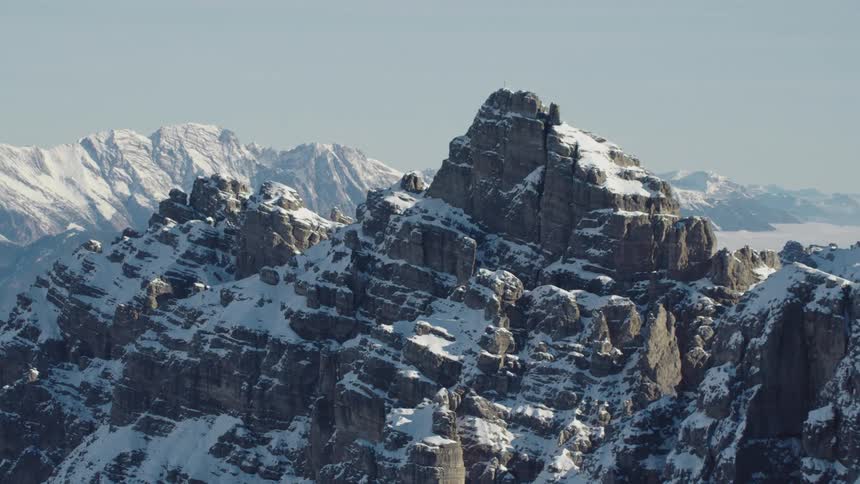 Snow covered crevices of rugged mountains on misty day