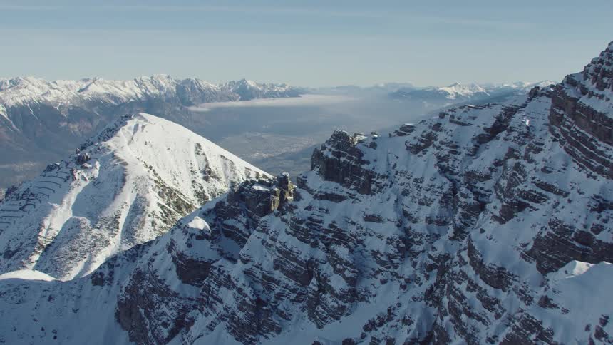 Aerial view of a valley between the snow covered peaks of a mountain range