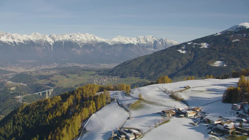 A neighborhood sits on a snow covered plateau on a mountain range