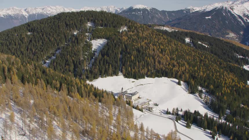 Aerial view of distant snowy mountains and building in a valley