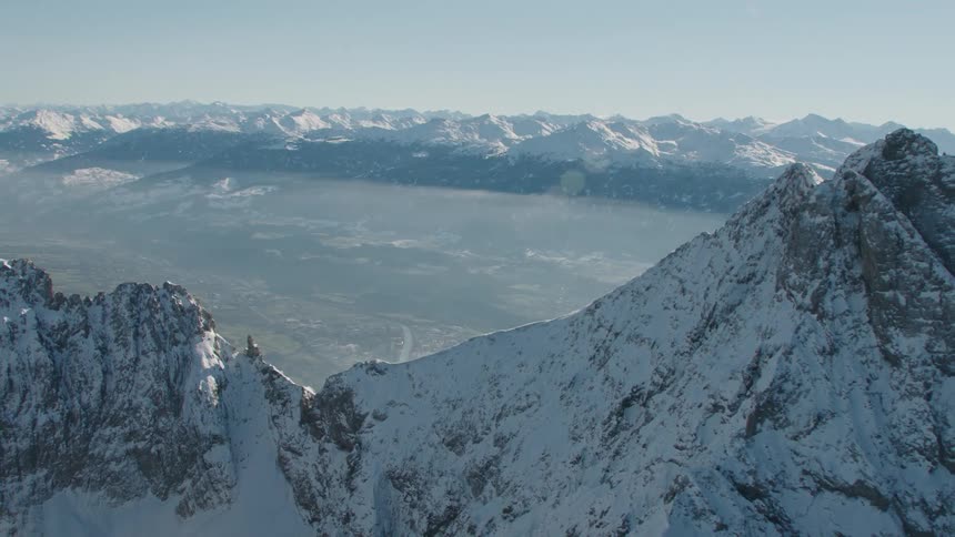 Path winds through misty valley surrounded by snow covered mountains