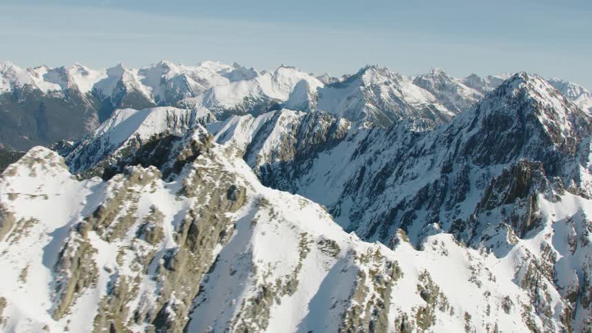 Snow covered rugged mountains stretch to horizon