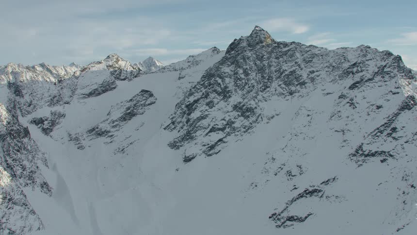 Snow covered mountains stretch to the horizon on cloudy day
