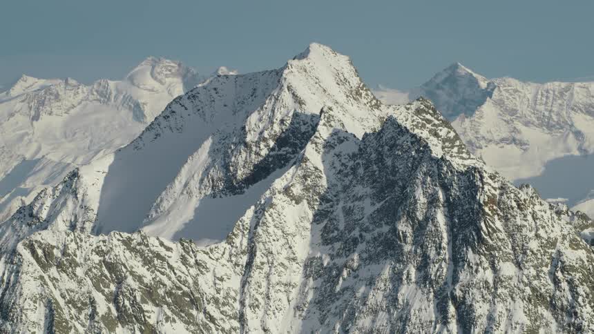 Aerial view of the snow covered slopes and cliffs of a mountain peak