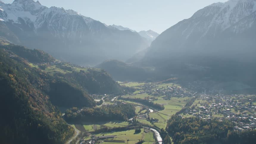 Aerial view of high snowy mountains and small town next to river