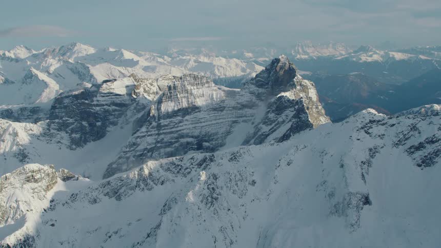 An aerial view of a mountain range covered in snow in the day