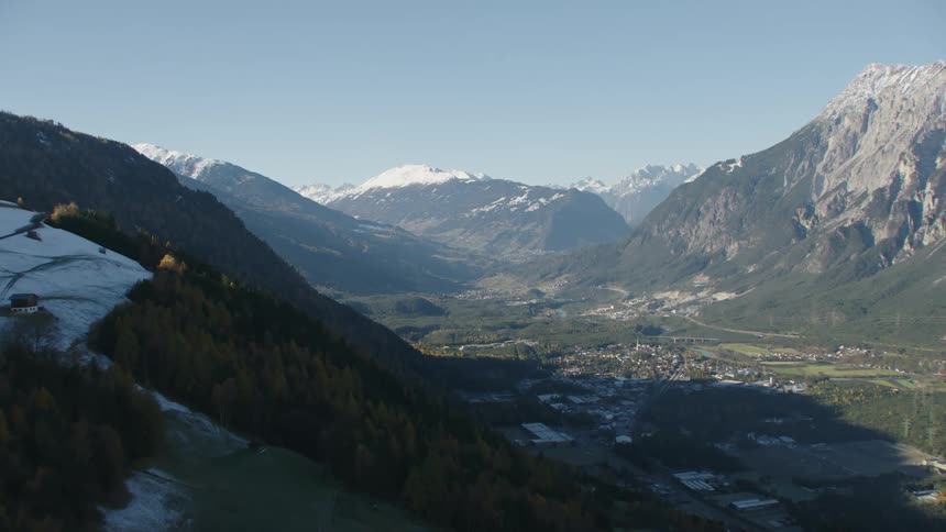 Aerial view of a small town in a valley surrounded by the snow covered mountain peaks