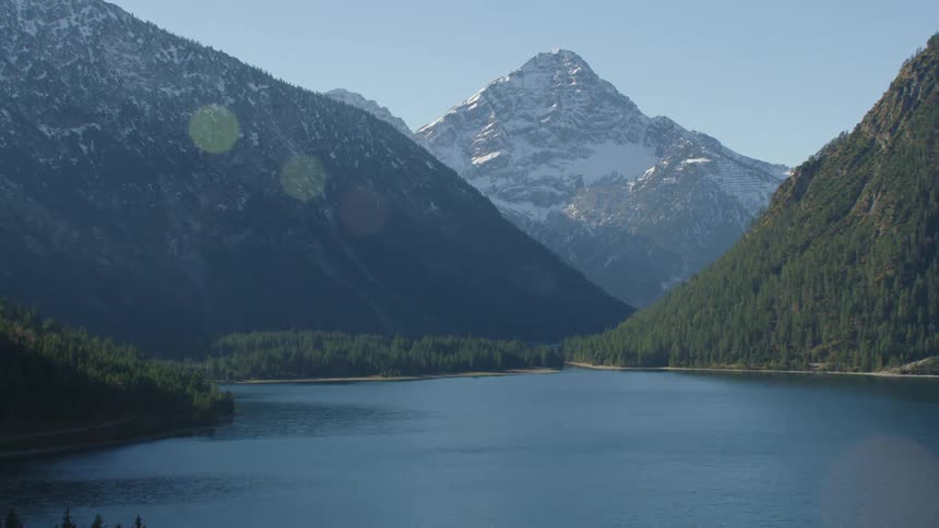 Aerial view of still lake surrounded by high mountains on sunny day