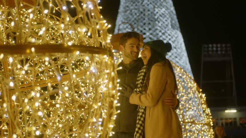 A couple stands next to a lit ball