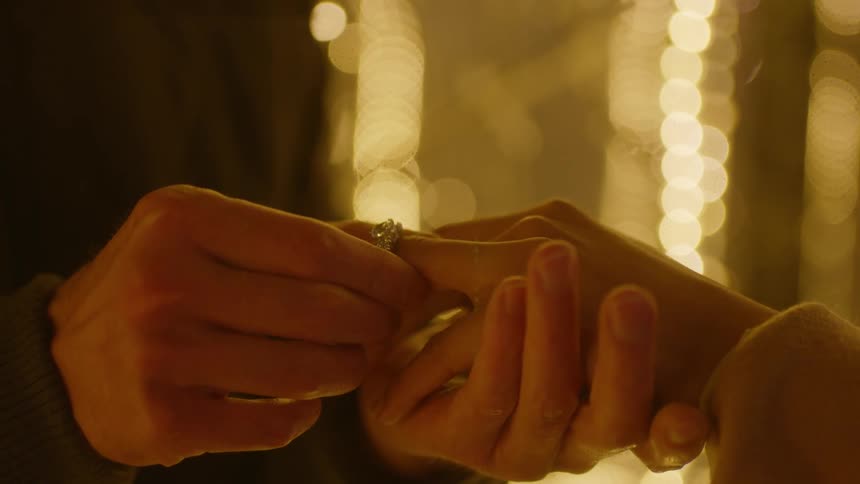 A man puts a wedding ring on a womans hand as he holds her hand