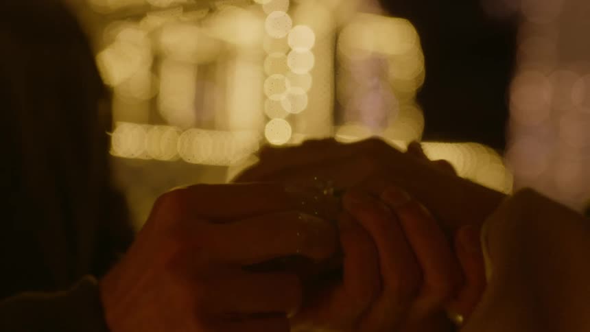 A man placing a ring on a womans finger before holding her hand