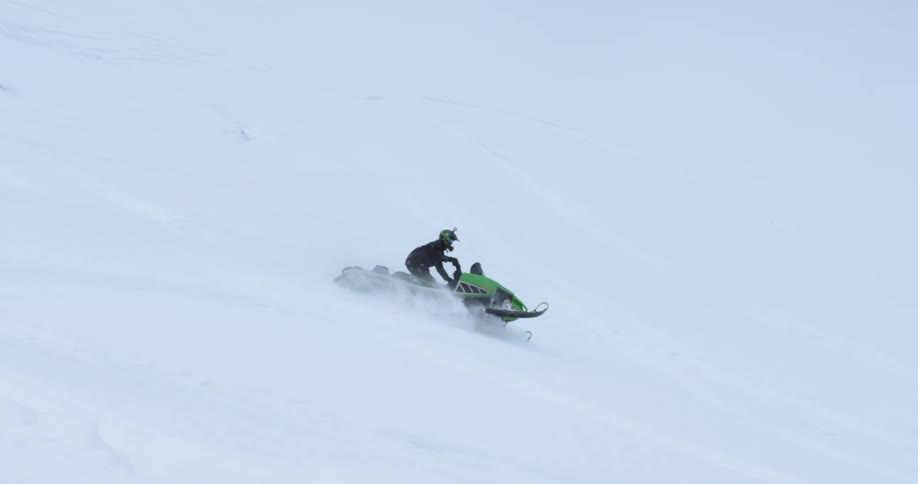 A person is riding a snowmobile down a snowy hill