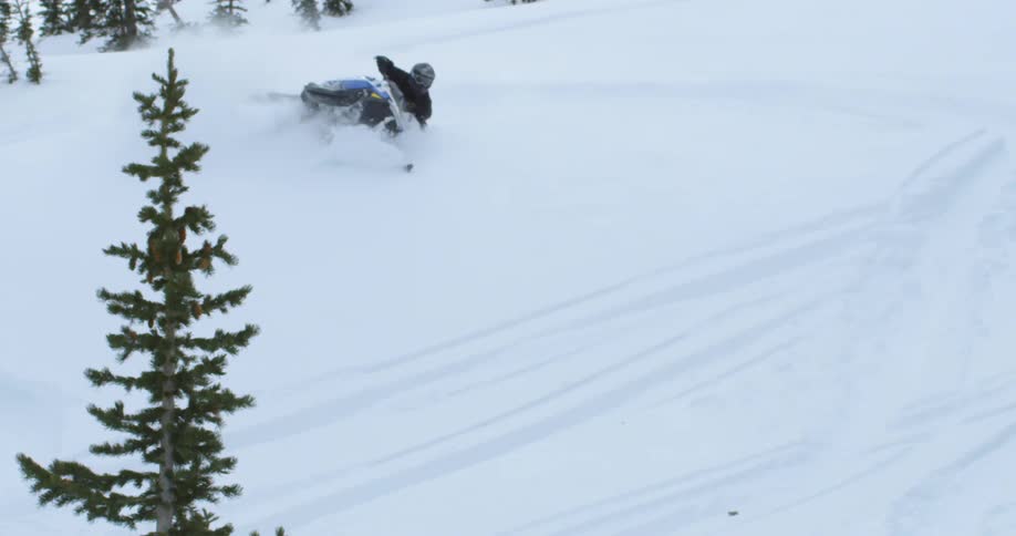 Snowmobile performs tricks on a snow covered hill