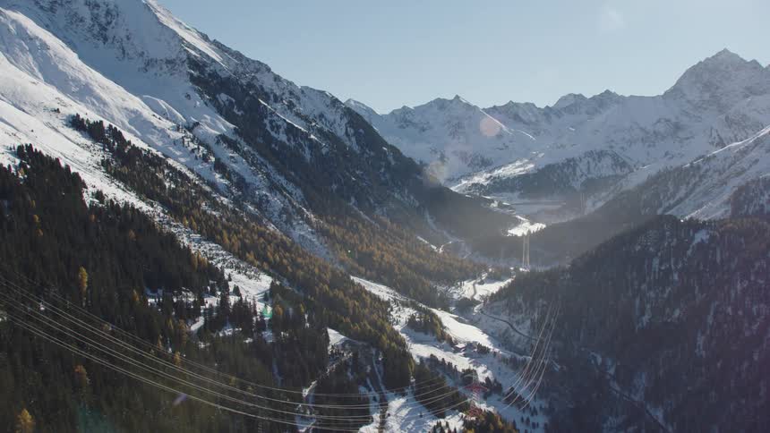 A small community in in a valley surrounded by snowy mountains and forest