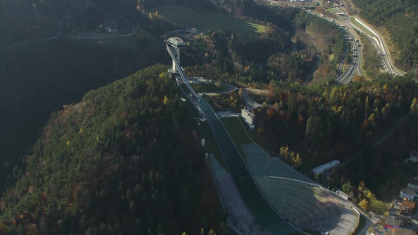 A daytime aerial view of a ski sports training facility in a town located in a forested mountain
