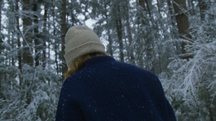 A woman smiling then turning around and walking in the snow