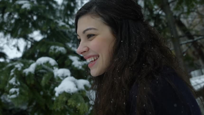 A woman is smiling as it snows around her