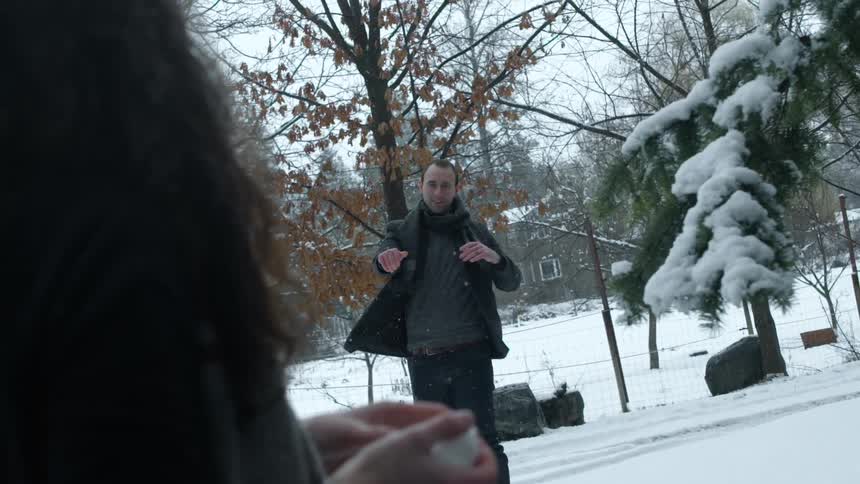 A man throws a snowball at a woman