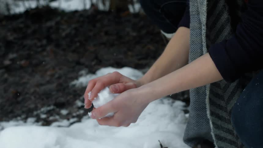 A person picks up snow to create a snowball