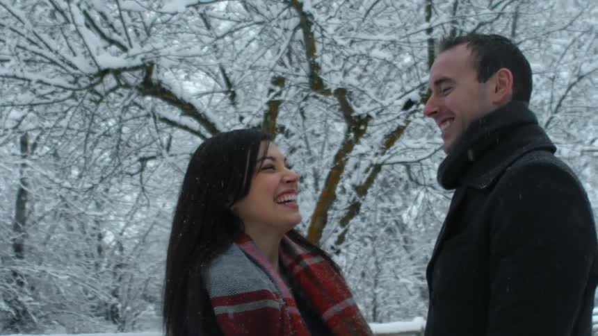 Snow falling on a man and woman as they laugh
