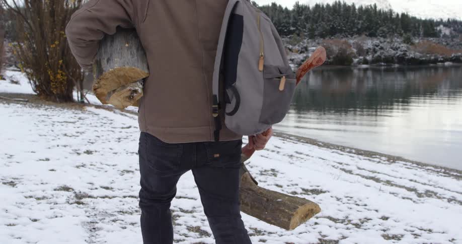 A man is carrying firewood in the snow