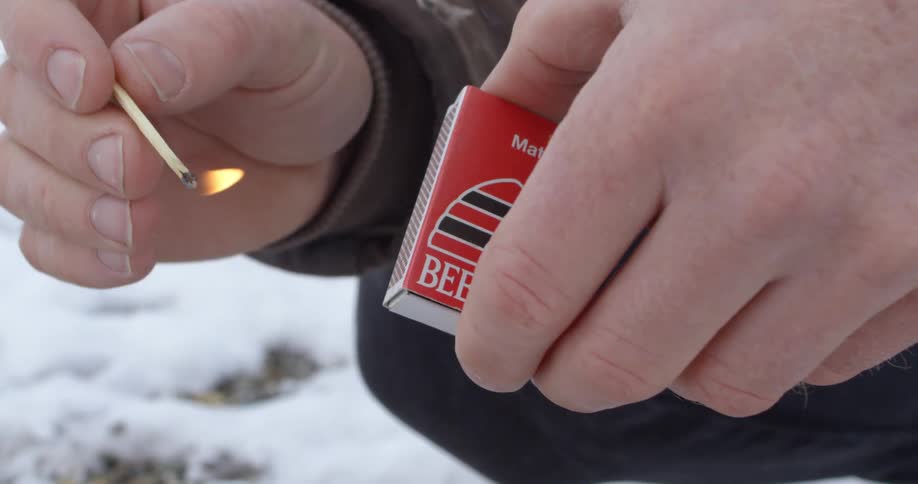 Man lights a match then shields it from going out