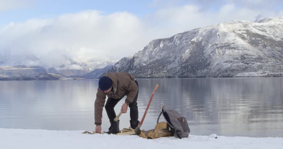 Man gathering up firewood on a snowy beach