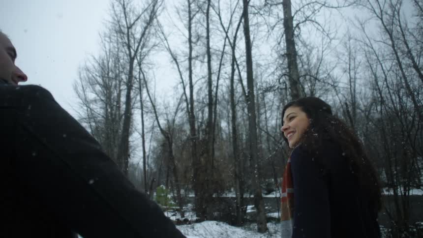 A man and woman walk together in the snow