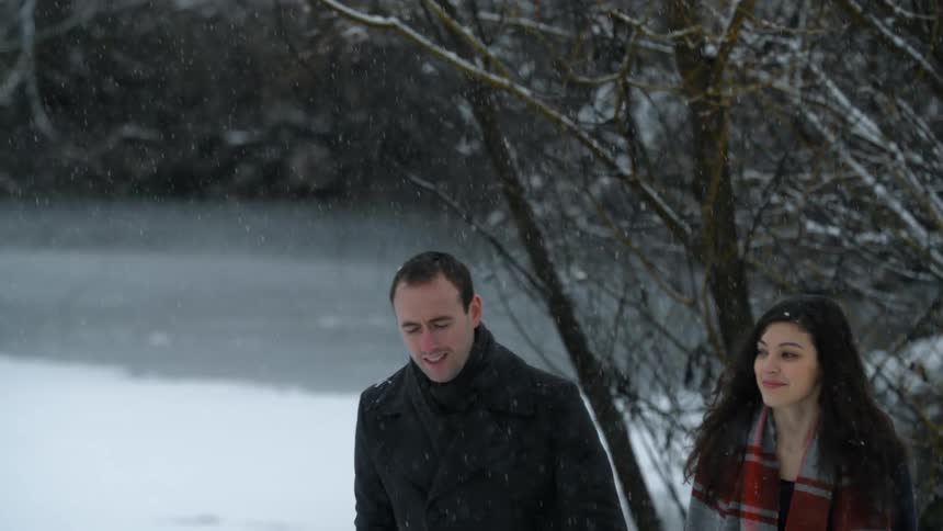 Man and woman smiling and talking as they walk in the snow fall