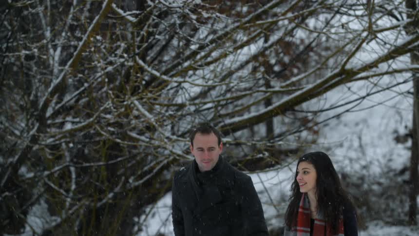 Man and woman walking and smiling while snow falls