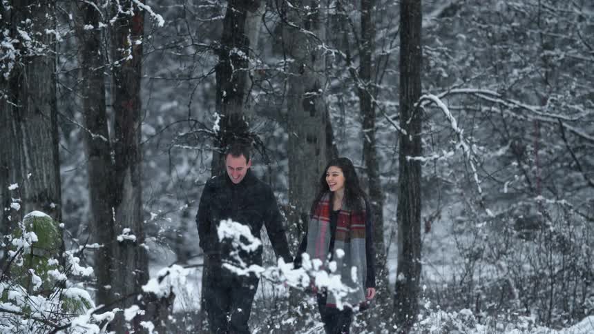 Couple walking through a snowy wilderness while holding hands